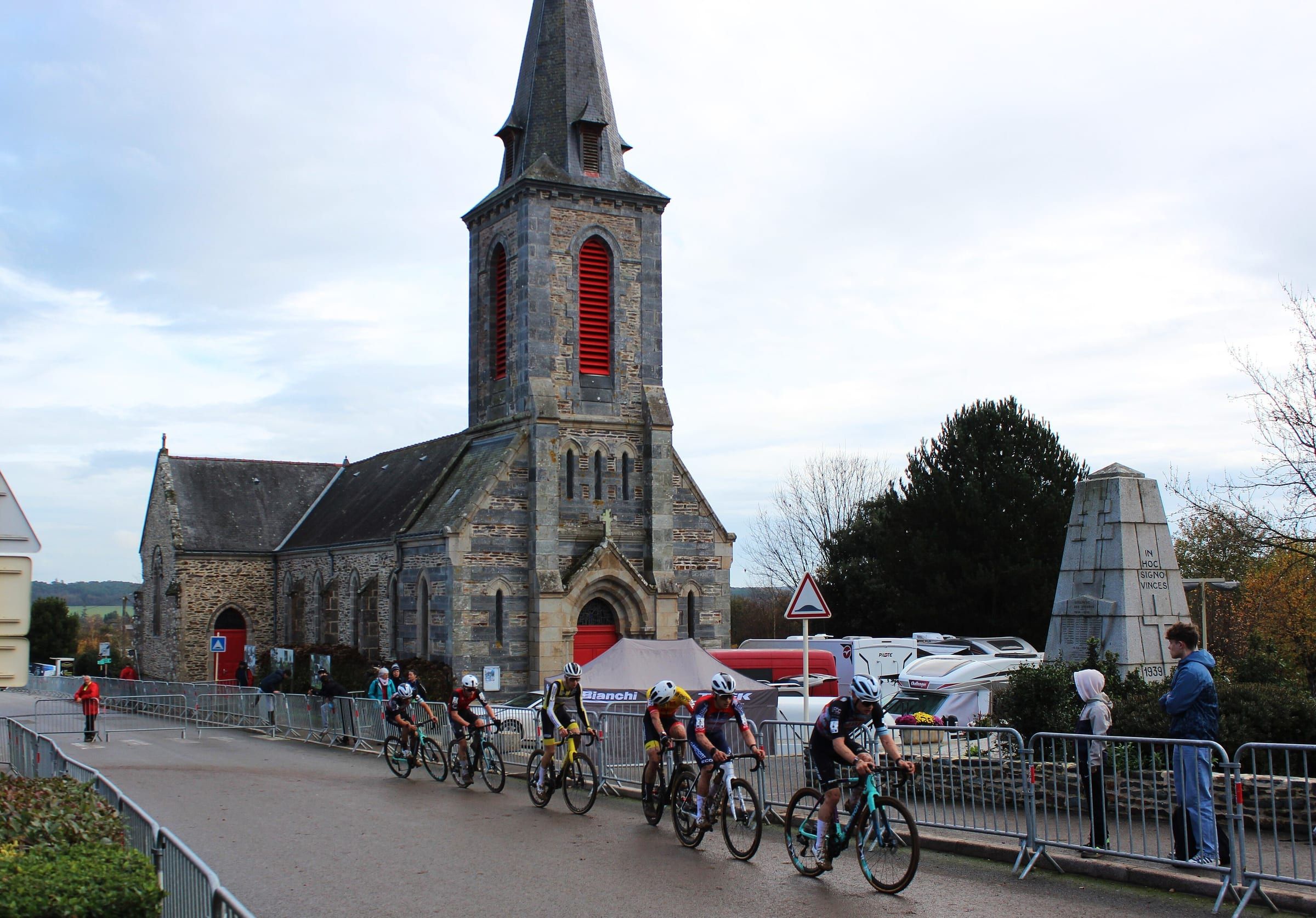 Un groupe de coureurs passe sur la route devant l'église de Quelneuc.