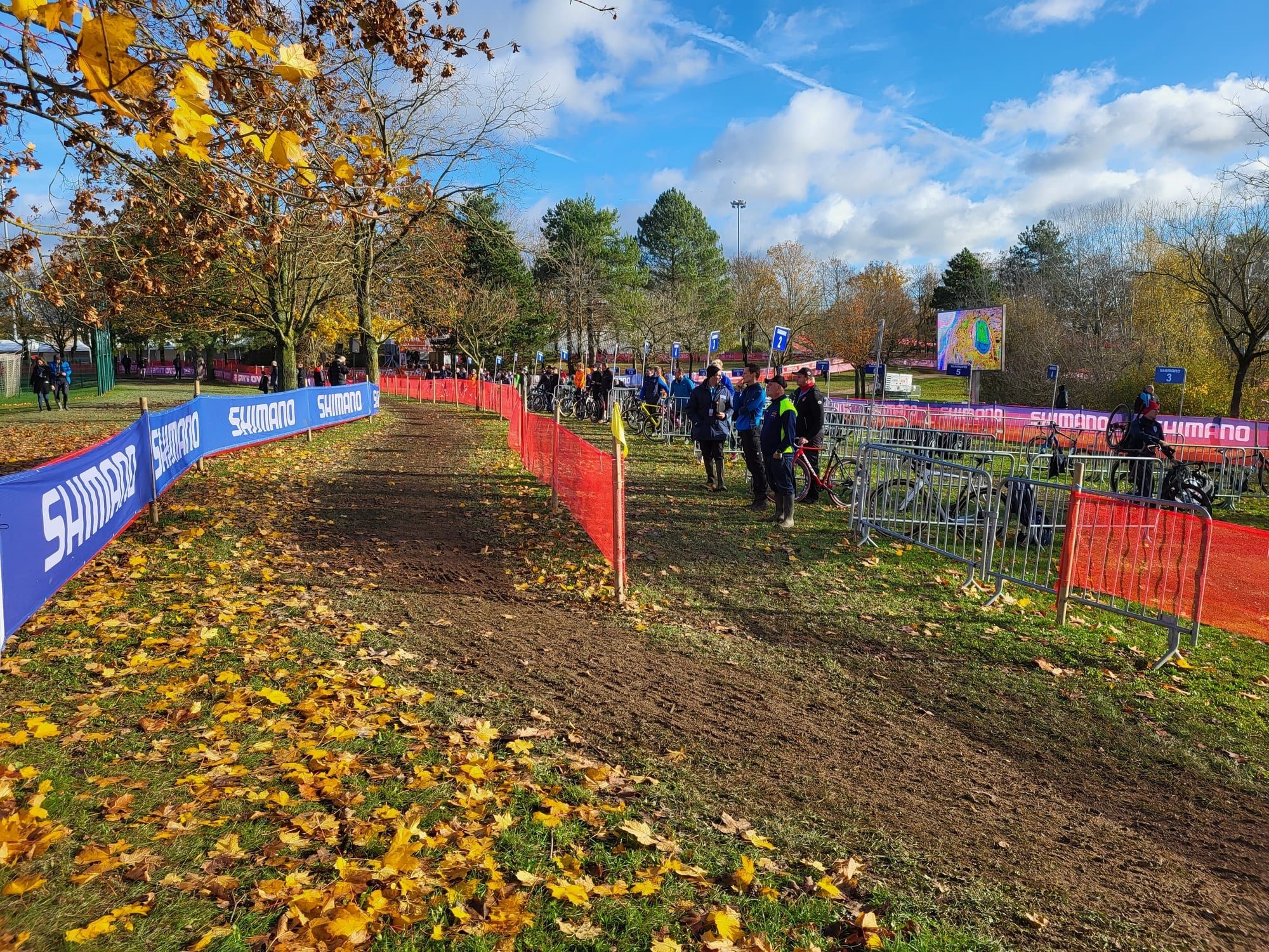 Le parcours tracé dans un parc couvert de feuilles d'automne, entre barrières bleues et filets orange.