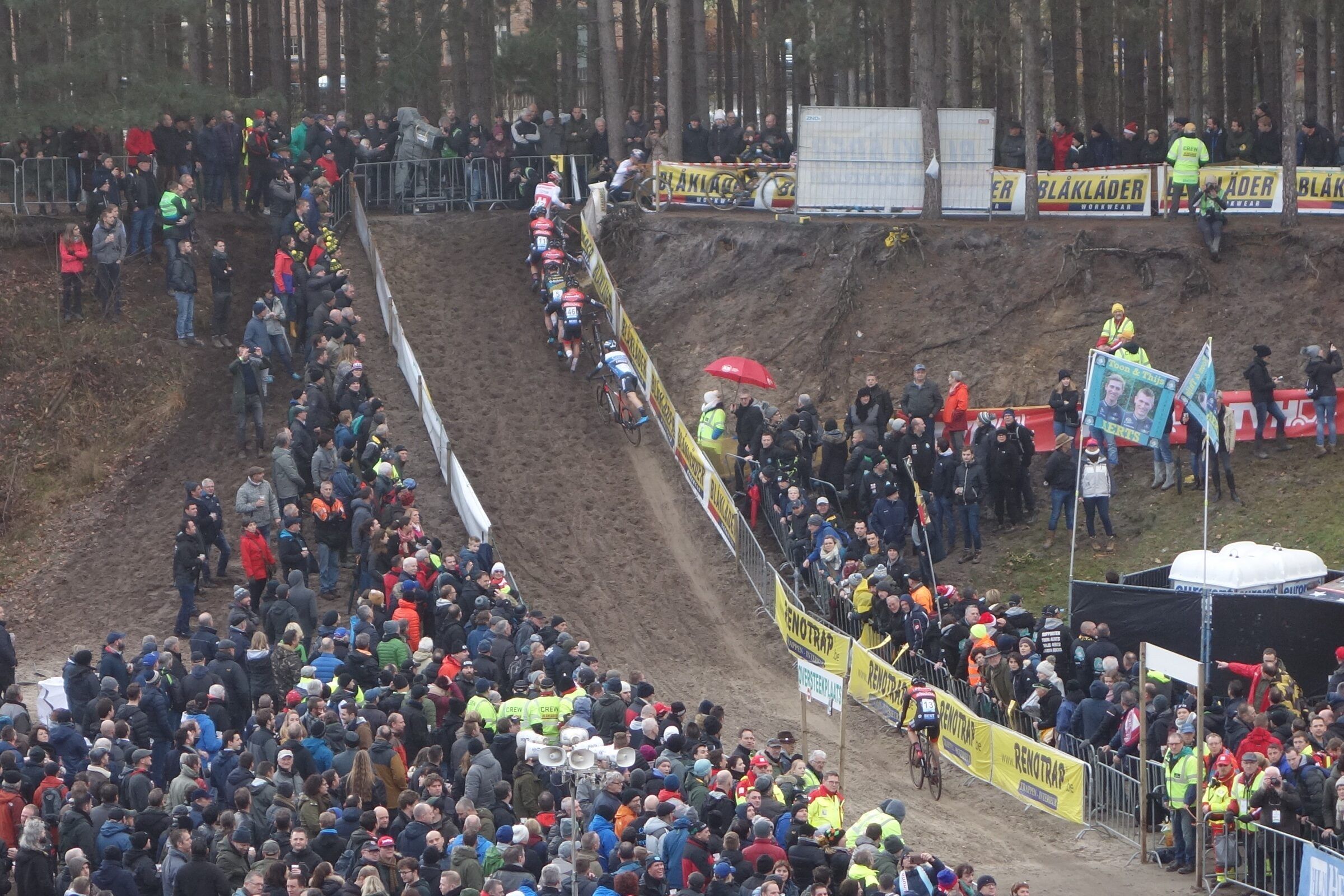 Des coureurs empruntent la longue pente de sable de la fosse de Zonhoven, bordée des deux côtés par une foule dense.